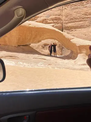 two people standing in a cave in the desert at سفينة الصحراء وادي رم in Disah