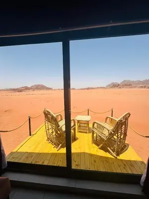 a porch with chairs and a table in the desert at Wadi Rum Bubble Dream in Wadi Rum
