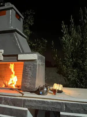 a fire oven with a pot and pans on a table at Pine Country Farm Stay in Umm al Manābī‘