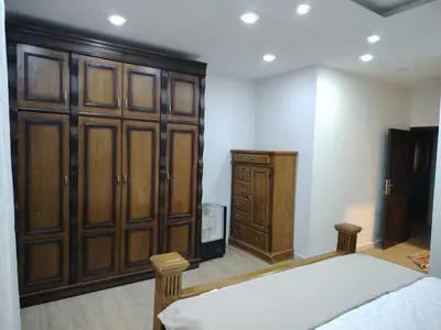 a bedroom with a bed and a wooden cabinet at Pine Country Farm Stay in Umm al Manābī‘