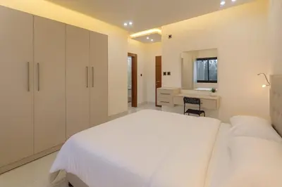 a white bedroom with a large white bed and a desk at Central Amman Twin Towers Apartment 2 in Amman