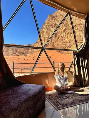 a woman sitting in a tent looking out at the desert at BUBBLE lUXURY RUM JNOPE CAMP in Wadi Rum