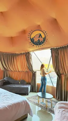 a woman standing in a hotel room with a table at WADI RUM BUBBlE AOSE CAMP in Wadi Rum