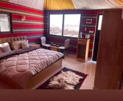 a bedroom with a bed and a desk and a window at Wadi Rum Wanderer cmap in Wadi Rum