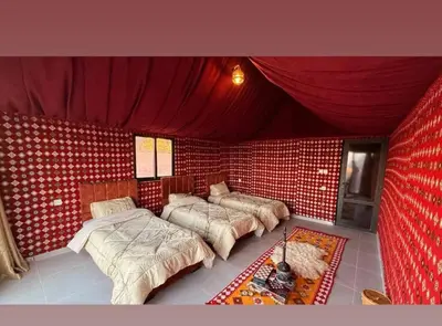 a room with three beds in a red brick wall at Wadi Rum Wanderer cmap in Wadi Rum