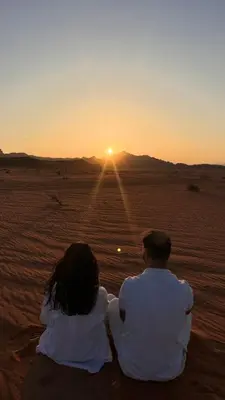 a man and a woman sitting in the desert watching the sunset at Desert soul in Wadi Rum
