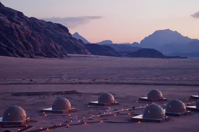 a group of domes in the desert with mountains at Sunrise Echo Camp in Wadi Rum