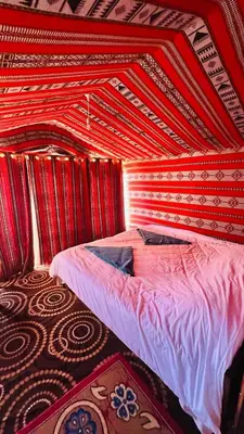a bed in a room with a red wall at Desert Nights camp in Aqaba