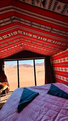 a bed in a room with a view of the desert at Desert Nights camp in Aqaba