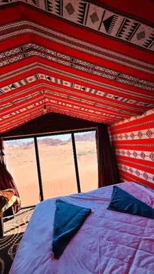 a bed in a room with a view of the desert at Desert Nights camp in Wadi Rum
