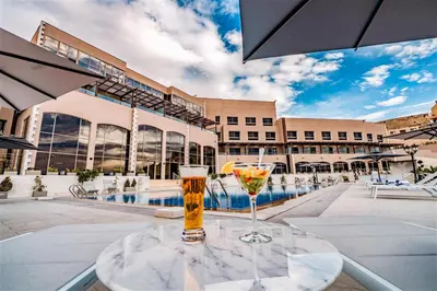 two glasses of beer sitting on a table in front of a pool at Petra Pillars Luxury Hotel in Petra