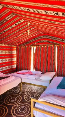 a room with three beds in it with red walls at Desert Nights camp in Aqaba