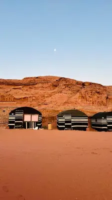 three domes in the desert with a mountain in the background at Desert Nights camp in Aqaba