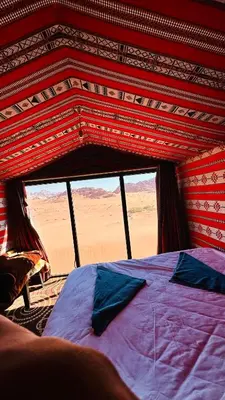 a bed in a tent with a view of the desert at Desert Nights camp in Wadi Rum