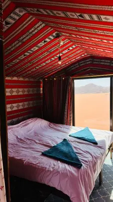 a bed with two blue pillows on top of it at Desert Nights camp in Wadi Rum