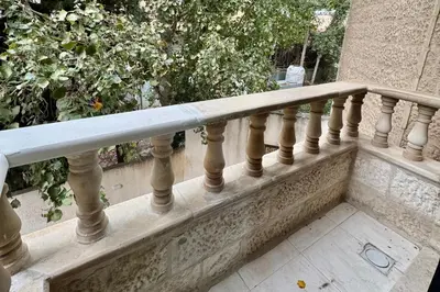 a stone railing on a balcony with trees in the background at Central Budget Stay in Amman