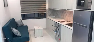 a small kitchen with a washing machine and a blue couch at غزو 15 in Aydūn