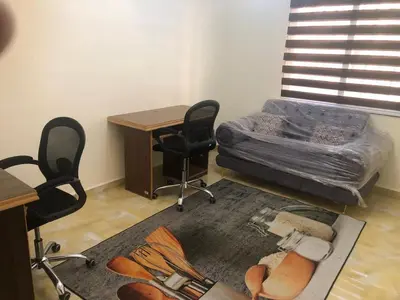 a room with a desk and a bed and chairs at Irbid in Irbid