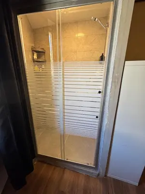 a glass shower door with blinds on it in a bathroom at Cozy Studio in a Creative Hub in Amman