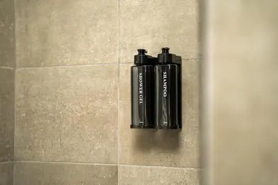 two black bottles sitting on a tile wall in a shower at Maria Suites 2 in Aqaba