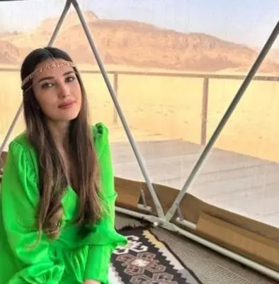 a girl in a green dress sitting next to a bed at Wadi Rum, the best stars in Wadi Rum