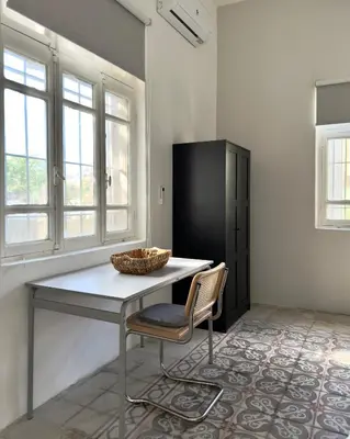 a table and a chair in a room with windows at Turath by Badiya 2BR Apt In Luweibdeh in Amman