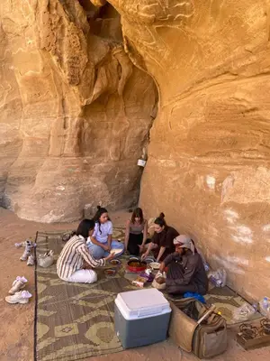a group of people sitting on the ground in a cave at Desert Time in Wadi Rum
