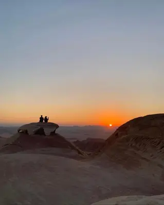 two people sitting on a rock watching the sunset at Desert Time in Wadi Rum