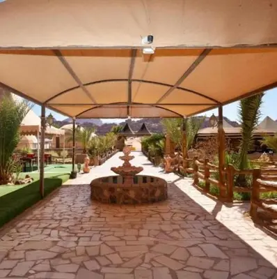 a patio with a large umbrella and a fountain at Wadi Rum Salem in Wadi Rum