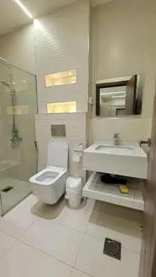 a white bathroom with a toilet and a sink at Lavender Résidence in Amman