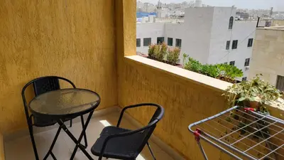 a balcony with two chairs and a table and a window at Lavender Résidence in Amman