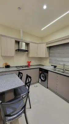 a kitchen with a sink and a table and a washing machine at Lavender Résidence in Amman