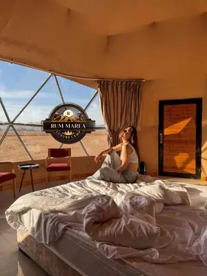 a woman sitting on a bed in a bedroom at RUM MAREA lUXURY CAMP in Wadi Rum
