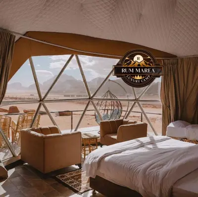 a bedroom with a bed and chairs and a view of the desert at RUM MAREA lUXURY CAMP in Wadi Rum