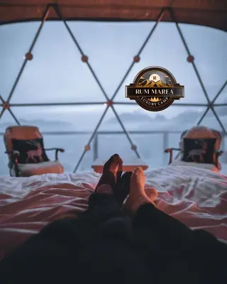 a person laying on a bed with their feet up at RUM MAREA lUXURY CAMP in Wadi Rum