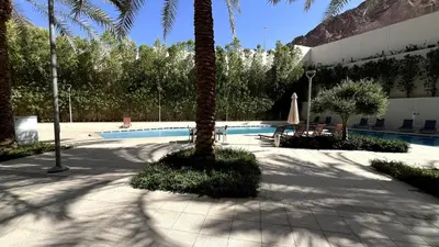 a palm tree sitting next to a swimming pool at Luxury Suite in Aqaba AlRaha Village Marsa Zayed in Aqaba
