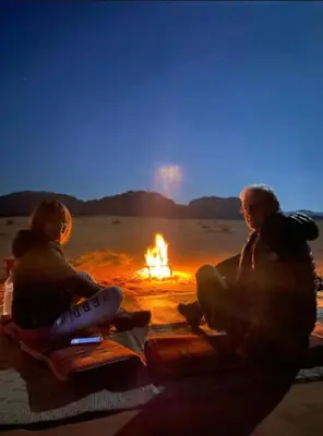 two people sitting around a fire in the desert at Wadi Rum Karolina Bubbles camp in Wadi Rum