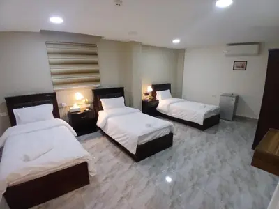 a hotel room with two beds and two tables at Kahraman Amman Hotel in Amman
