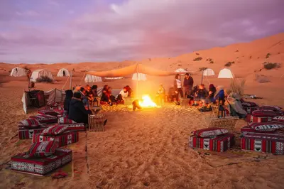a group of people sitting around a fire in the desert at 1moon valley camp in Al Jafr