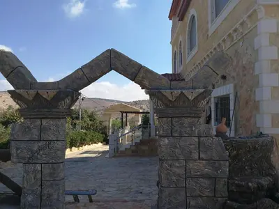 a stone archway in front of a building with a bench at Green Hills in Ajloun