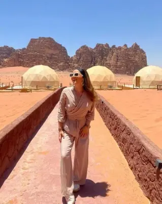 a woman standing next to a wall in the desert at Camb wadi Rum in Disah