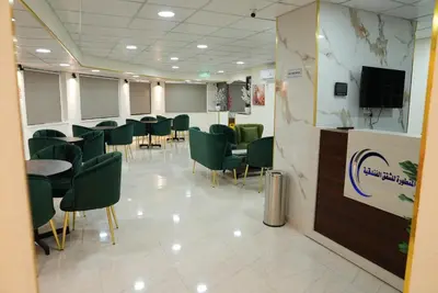 a waiting room with green chairs and a tv at المتطورة للشقق الفندقية in Amman