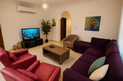 a living room with red furniture and a flat screen tv at Family Deluxe Apartment in Amman