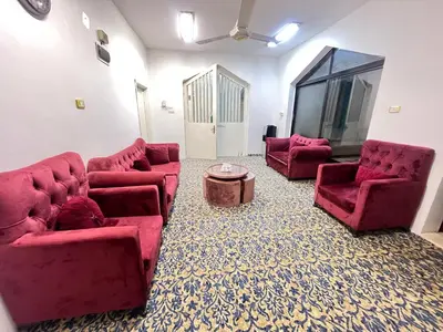 a living room with red couches and a table at دار الخير للشقق المفروشة in Al Mafraq