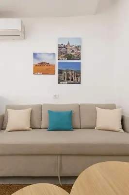 a couch in a living room with three pictures on the wall at Rainbow Street Studio Cozy Central in Amman