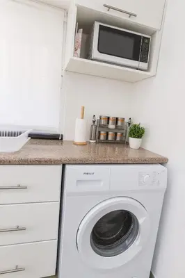 a kitchen with a washing machine and a microwave at Rainbow Street Studio Cozy Central in Amman