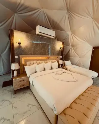 a bedroom with a large bed with a tv on the wall at Wadi Rum Emerald Camp in Wadi Rum
