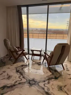 a room with two chairs and a table and a large window at Alma chalets in Aş Şarīḩ
