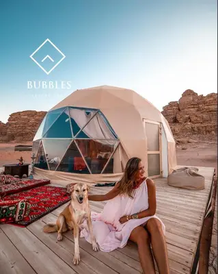 a woman and a dog sitting next to a tent at BUBBLES LUXURY CAMp in Wadi Rum