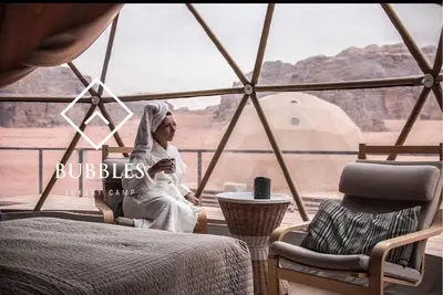 a woman sitting in a tent looking out at the desert at BUBBLES LUXURY CAMp in Wadi Rum